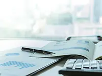 Charts and financial report besides pen and keyboard