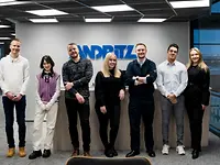 ANDRITZ trainees standing in a line before an ANDRITZ logo on a wall