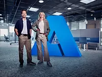 ANDRITZ employees in a modern office standing by ANDRITZ-logo sign